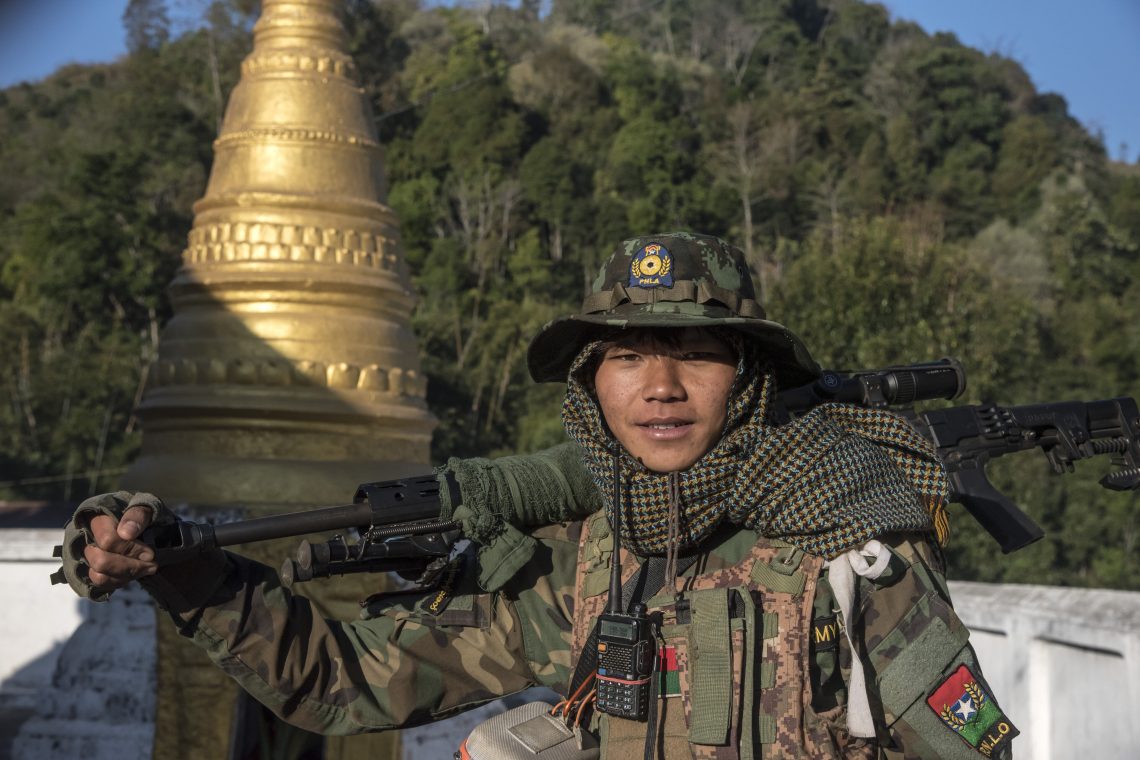 A young soldier fighting the Burmese junta stands in front of a Buddhist pagoda in a Pa-o ethnic village.
